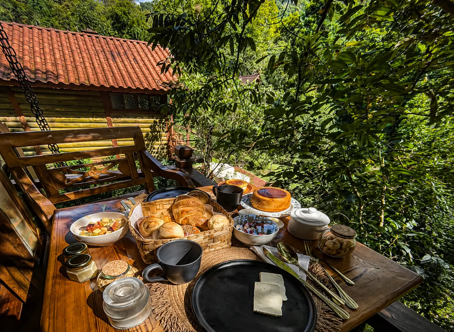 Mesa de café da manhã artesanal com vista para a mata e os chalés
